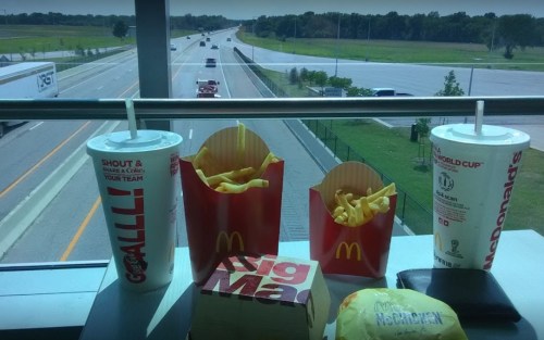 A view of a highway with McDonald's fries, drinks, and a Big Mac in the foreground.