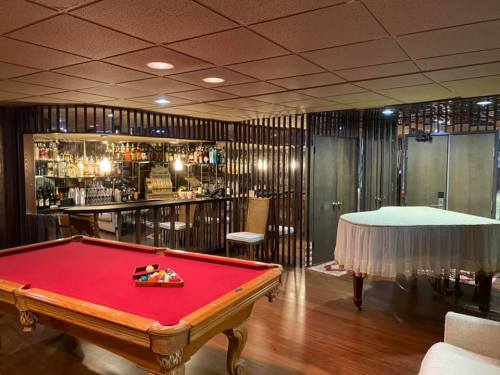 A cozy basement lounge featuring a red pool table, a bar with drinks, and a piano in a stylish setting.