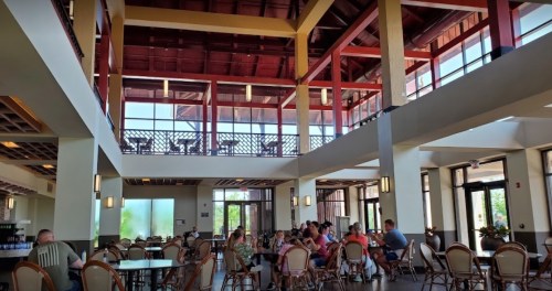 A spacious dining area with high ceilings, large windows, and tables filled with people enjoying their meals.