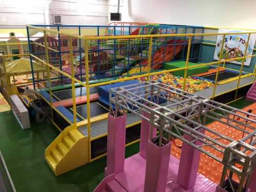 A colorful indoor play area featuring climbing structures, ball pits, and slides for children.