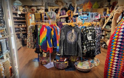 A colorful display of clothing and accessories in a vibrant shop, featuring rainbow and patterned garments.