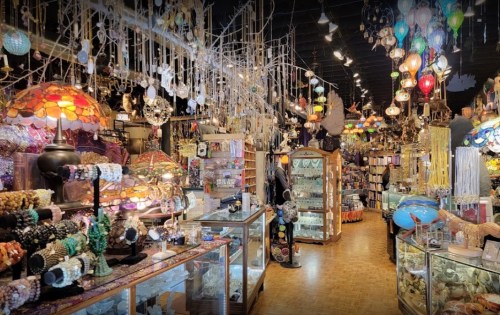A vibrant shop filled with colorful lamps, jewelry, and decorative items, creating a whimsical and inviting atmosphere.