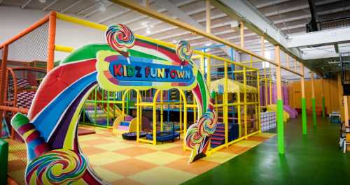 Colorful entrance to Kidz Funtown, featuring play structures and soft surfaces in a vibrant indoor playground.