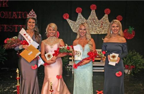 Four pageant winners stand on stage, holding trophies and flowers, with crowns and decorations in the background.