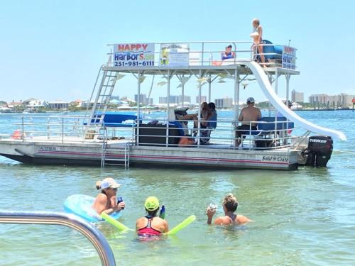 A group of people in the water enjoying a sunny day near a boat with a sign for Happy Harbors.