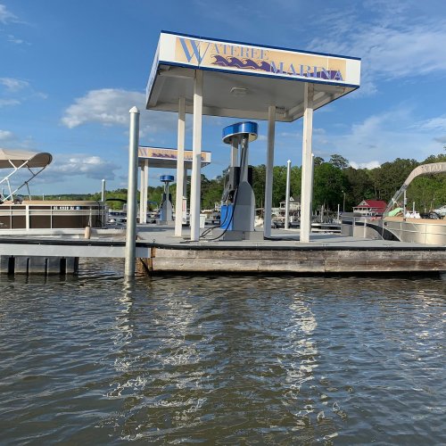 A marina with a fuel dock and boats on calm water under a blue sky with scattered clouds.