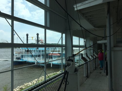 View of a riverboat docked outside a building, with large windows and a person standing nearby.