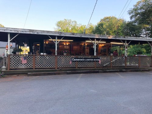 Exterior view of Cameron's Lobster House, featuring a wooden deck and decorative elements, surrounded by trees.