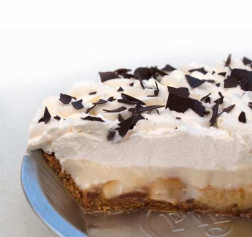 A creamy dessert with layers of whipped topping, chocolate shavings, and a graham cracker crust.