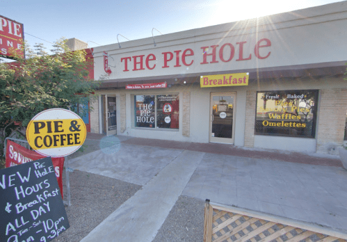 Exterior of "The Pie Hole" restaurant, featuring a sign for breakfast, pies, and coffee. Bright, sunny day.