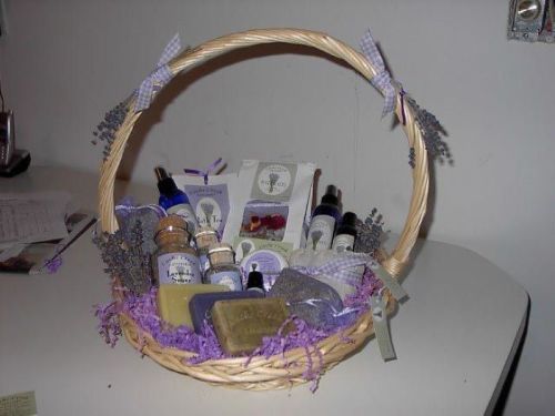 A woven basket filled with lavender-themed products, including soaps, oils, and a sachet, decorated with purple ribbons.