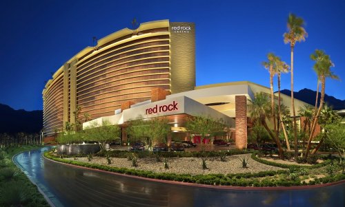 Exterior view of Red Rock Casino at dusk, featuring modern architecture and palm trees against a blue sky.