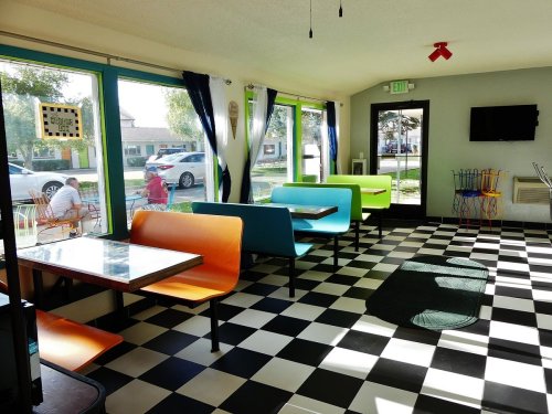 Brightly colored seating in a diner with a checkered floor and large windows, creating a cheerful atmosphere.