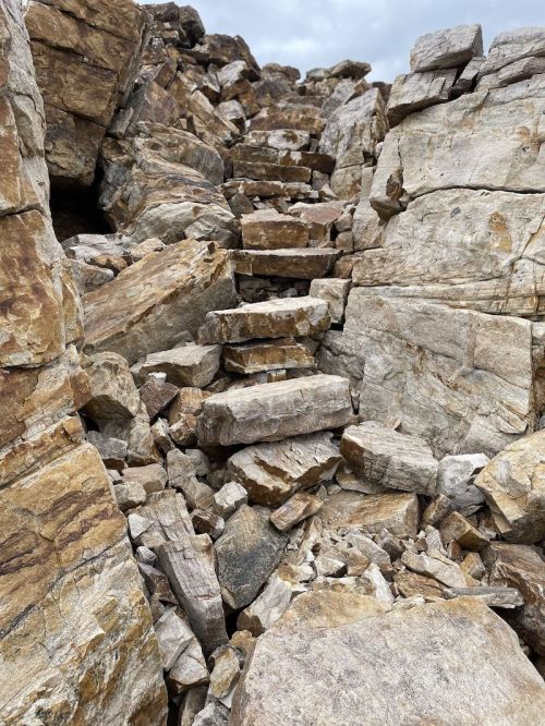 Rocky staircase leading up through a rugged terrain of large, uneven stone blocks.