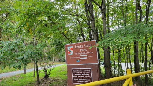 Sign for Rocks State Park's Falling Branch Area, surrounded by trees and a pathway in the background.