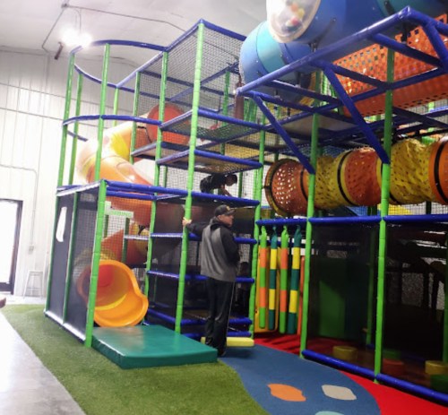 A colorful indoor play structure with slides and climbing areas, featuring children playing and exploring.