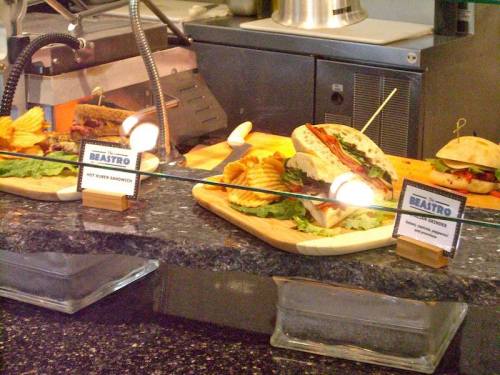 A display of sandwiches and chips on wooden platters at a restaurant counter.