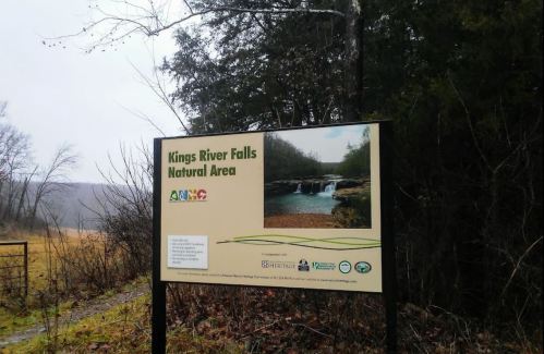 Sign for Kings River Falls Natural Area, featuring a photo of the falls and surrounding nature.