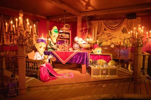 A whimsical room with colorful decorations, plush characters, and candlelight, creating a magical atmosphere.