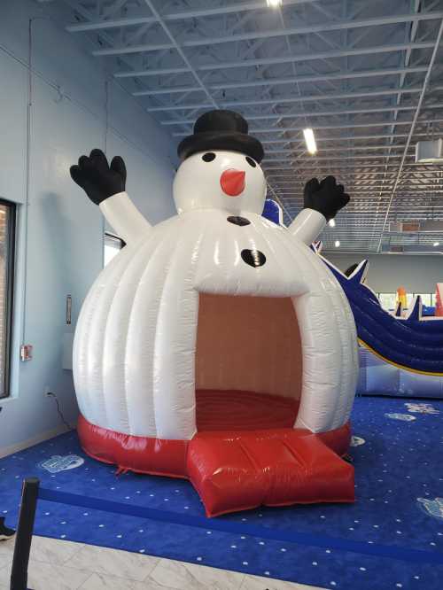 A large inflatable snowman with a black hat and arms raised, serving as an entrance to a bounce house.