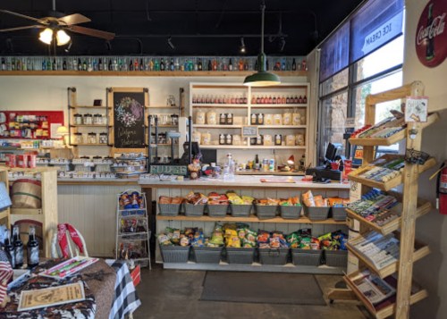 A cozy store interior featuring shelves of snacks, drinks, and local products, with a rustic wooden counter.