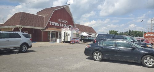 A view of Kidron Town & Country store with parked cars and a blue sky in the background.