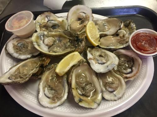 A platter of fresh oysters on the half shell, garnished with lemon wedges and served with dipping sauces.