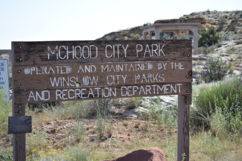 Sign for McHood City Park, maintained by Winslow City Parks and Recreation Department, with rocky landscape in the background.