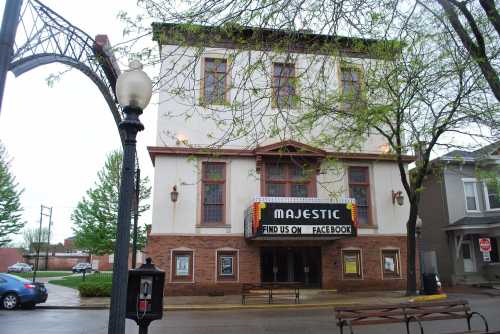 Historic Majestic Theater with marquee, surrounded by trees and a street lamp on a rainy day.