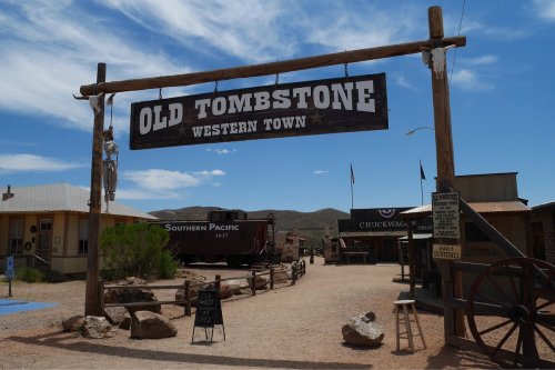 Sign for "Old Tombstone Western Town" at an outdoor historical site with buildings and a clear blue sky.