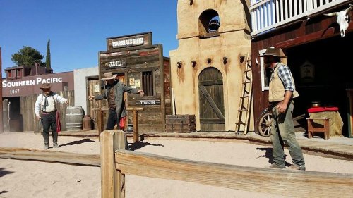 A western-themed scene with three cowboys in a dusty town, featuring wooden buildings and a saloon.