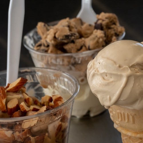 Two cups of ice cream: one with cookie dough and chocolate chunks, the other with chopped almonds, plus a cone of vanilla.