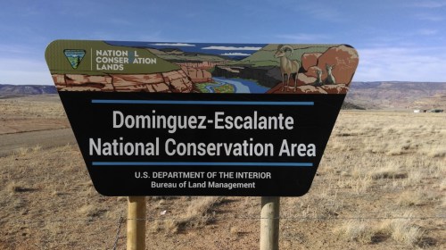 Sign for Dominguez-Escalante National Conservation Area, featuring scenic landscapes and wildlife illustrations.