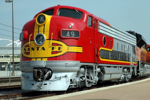 A vintage red and yellow Santa Fe train locomotive parked on a railway platform.
