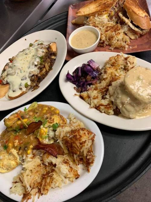 A platter of various hearty dishes, including loaded hash browns, biscuits with gravy, and colorful sides.