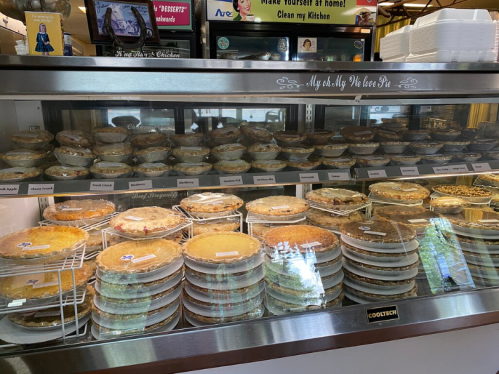 A display case filled with various pies, neatly arranged on shelves with labels for each type.