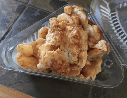 A triangular container filled with pieces of baked apple dessert, topped with a golden, sugary crust.