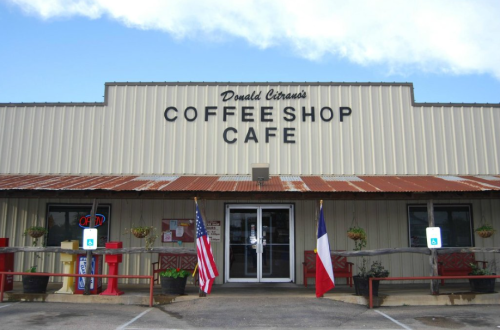Exterior of Donald Citrano's Coffee Shop Cafe, featuring an American flag and a Texas flag, with a welcoming entrance.