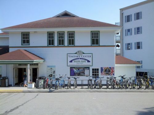 A white building with a red roof labeled "Visitor's Center," featuring parked bicycles in front.