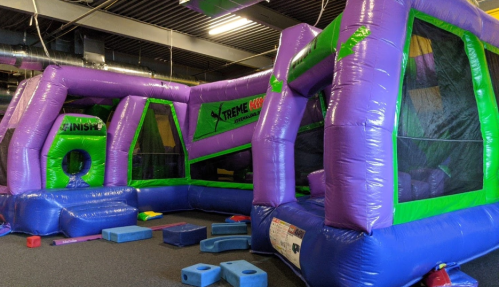 Colorful inflatable structures in a play area, featuring a finish line and various obstacles on the floor.