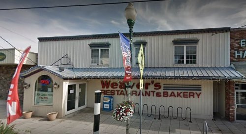 Exterior of Weaver's Restaurant & Bakery, featuring a sign, flags, and a bike rack in front of a two-story building.