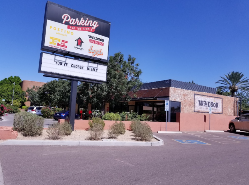 A restaurant building with a sign reading "Parking for the People" and "You've Chosen Wisely" under a clear blue sky.