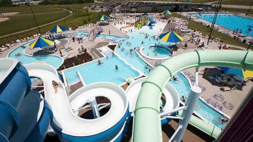 Aerial view of a water park featuring slides, pools, and colorful umbrellas with people enjoying the water.