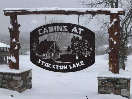 Sign for "Cabins at Stockton Lake" surrounded by snow-covered landscape and trees.