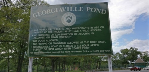 Sign at Georgiaville Pond outlining rules: valid stickers required, no alcohol, no dogs, and swimming restrictions.