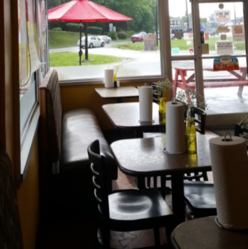 Cozy restaurant interior with tables, chairs, and a view of an outdoor patio under a red umbrella.