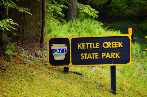 Sign for Kettle Creek State Park in Pennsylvania, surrounded by greenery and trees.