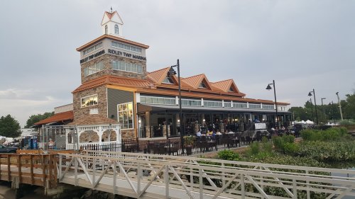 A waterfront restaurant with a large, multi-story building and a distinctive tower, surrounded by outdoor seating.