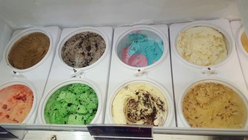A display of eight ice cream flavors in tubs, including chocolate, mint green, cotton candy, and more.