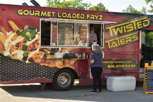 A food truck named "Twisted Taters" serving gourmet loaded fries, with a customer ordering at the window.